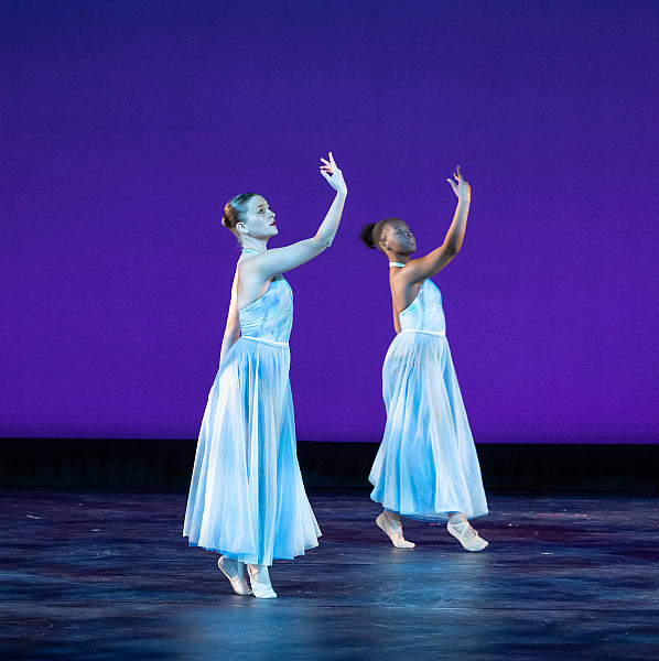 Two girls performing a synchronized dance routine on stage.
