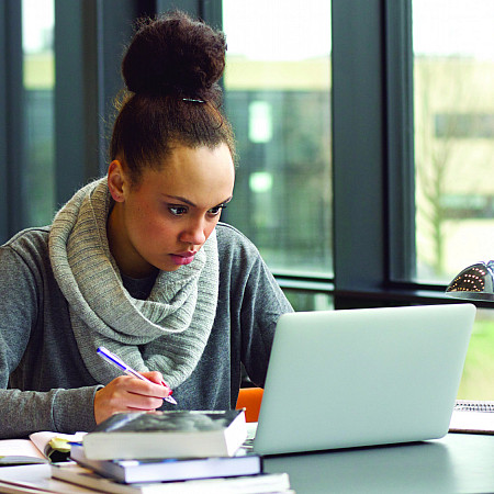 Female student taking notes on laptop