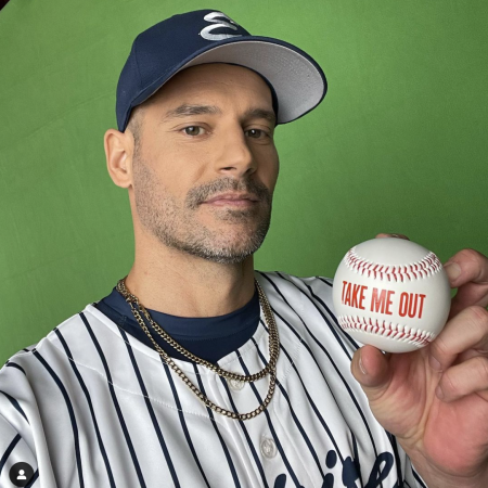 Eduardo Ramos holding up a baseball with inscription, Take Me Out.