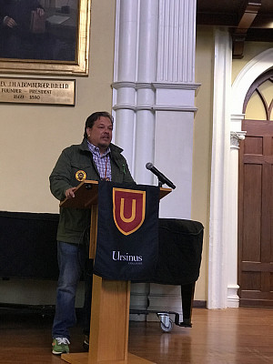 Man standing behind a Ursinus College podium giving a speech.