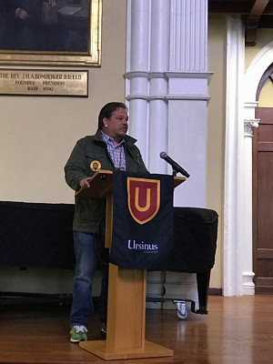 Man standing behind a Ursinus College podium giving a speech.