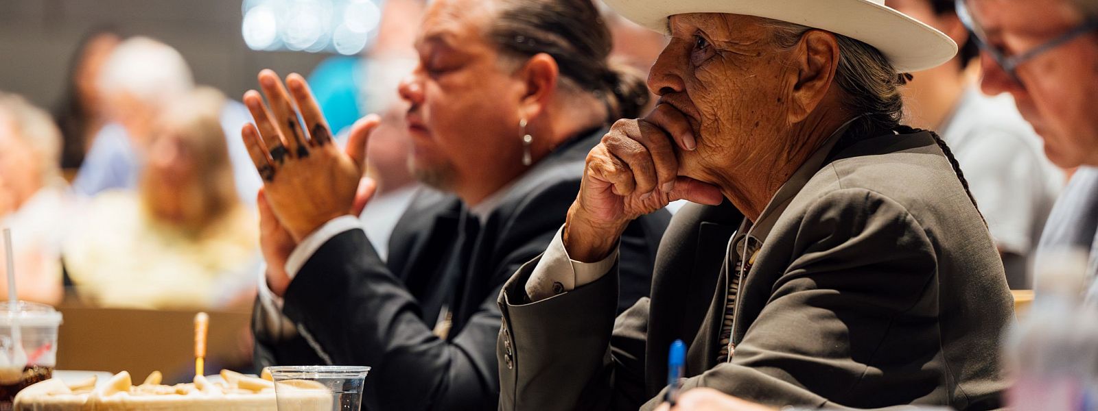 Close up of men sitting at a table listening to a presentation.