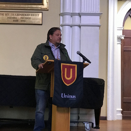 Man standing behind a Ursinus College podium giving a speech.