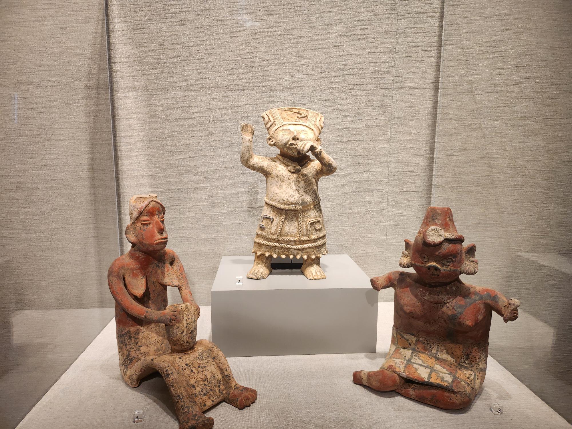 Three small figurines in an enclosed casing on display.