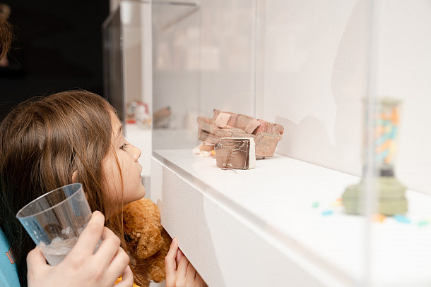 Child looking at miniature sculptures behind glass.