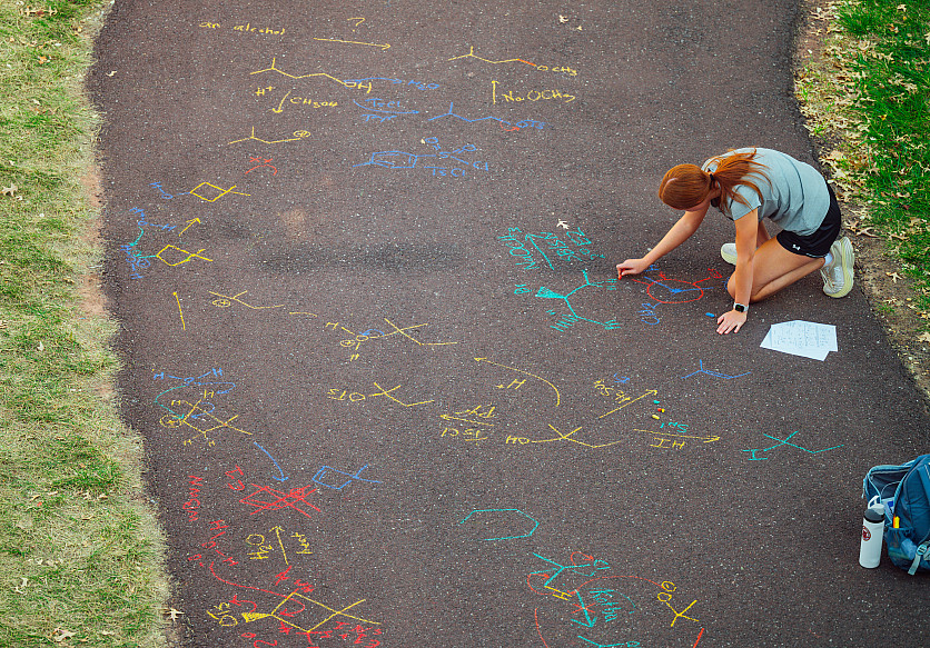 What else to do a sunny fall day? Take the class outdoors! A chemistry student participates in an outdoor class by chalking chemical stru...