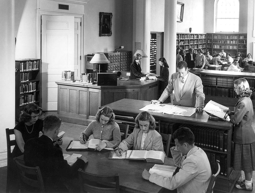 Old black and white photograph of students sitting in a library working individually.