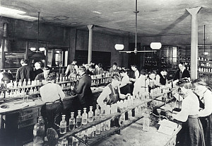 Old photograph of people working in an old fashion chemistry lab.