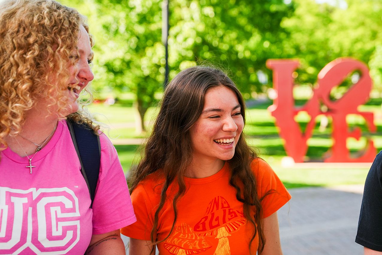 Close-up candid photo of college students laughing and conversating outside together.