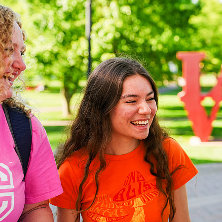 Close-up candid photo of college students laughing and conversating outside together.