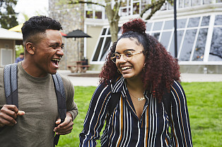 Two students laughing while walking through campus.